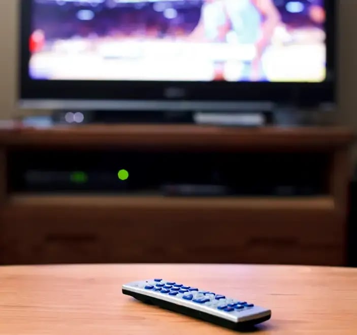 A blurred out TV with a remote control on a table.